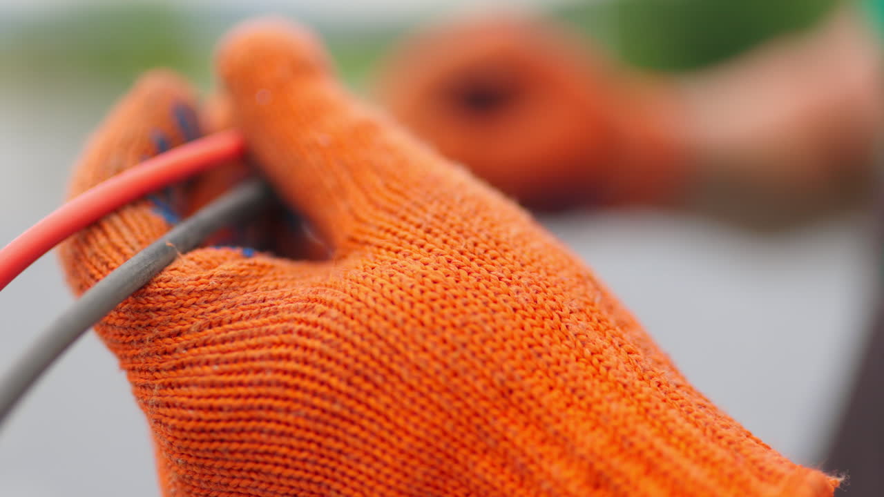 en manos con guantes naranjas conectando cables