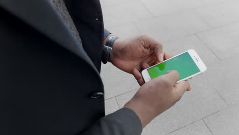 Businessman-working-on-cellphone-on-street.Executive-holding-smartphone-in-hands