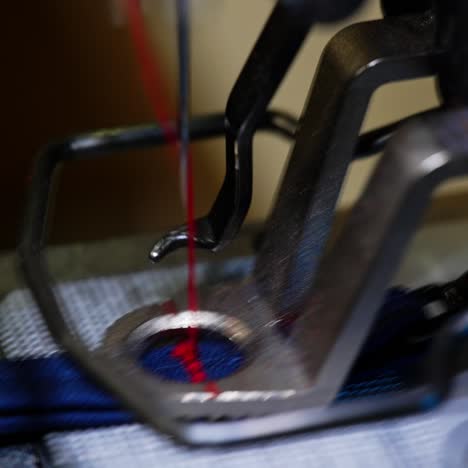 Sewing machine in motion. Tailor puts cloth under a sewing machine. Needle of a sewing machine makes a thread stitch. Macro shot