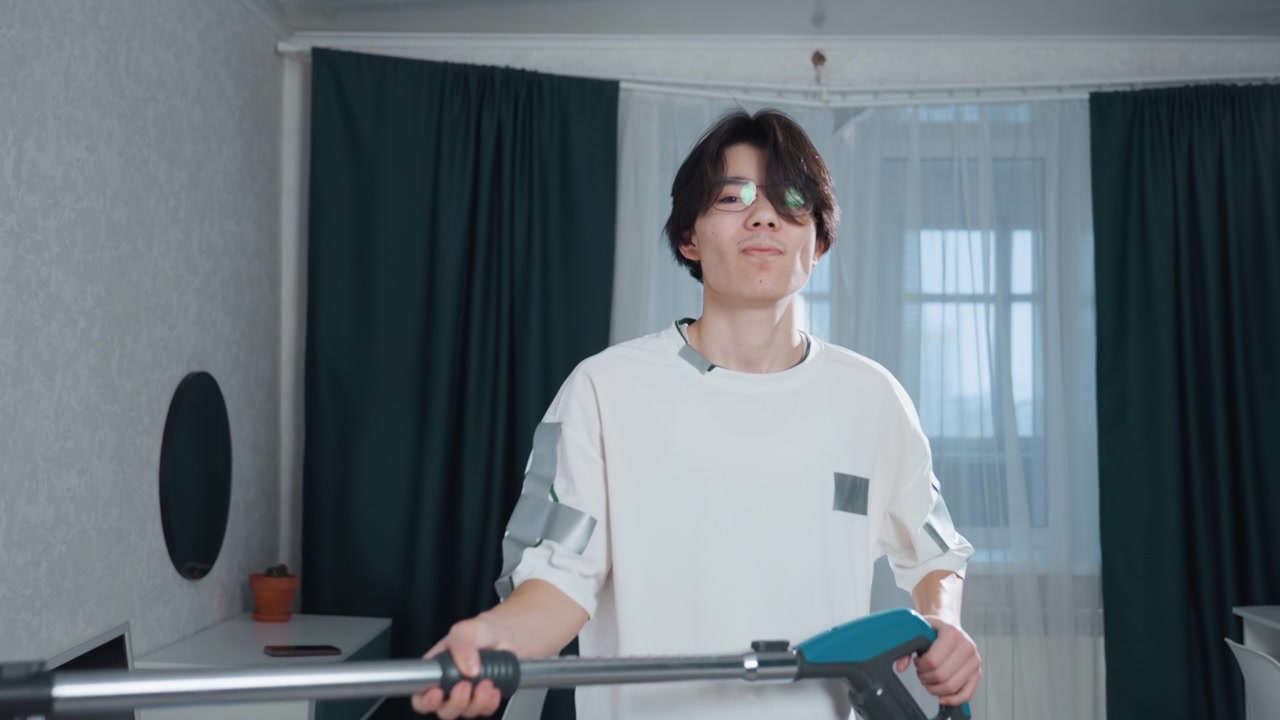 Asian man celebrating clean home after chores holding vacuum in triumphant pose, warm window light, curtain backdrop, confident smile, satisfied domestic mood, neat apartment lifestyle shot