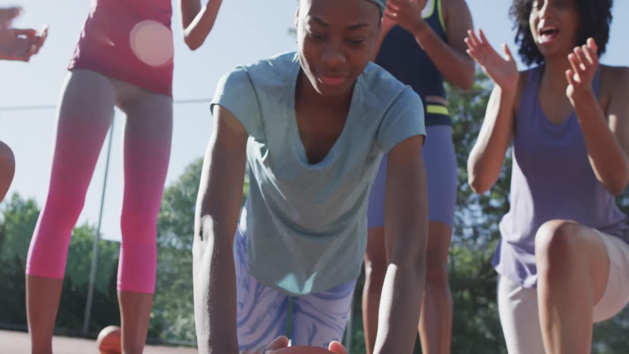 Happy diverse female basketball team training on sunny court, in slow motion