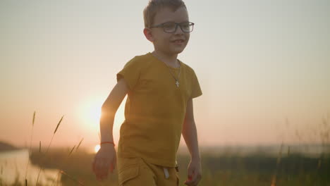 un niño con una camisa amarilla y pantalones cortos salta alegremente en un campo de hierba iluminado por el sol. la cálida luz del sol se filtra a través, creando un hermoso resplandor a su alrededor
