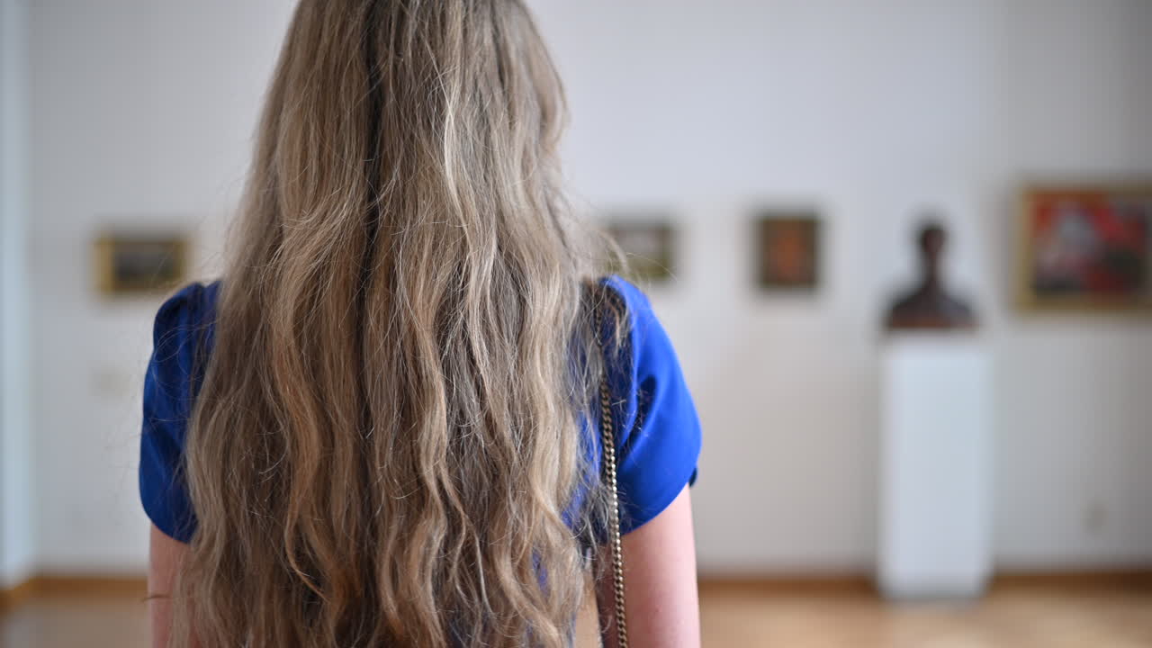Donna bruna in abito blu che si muove nel Museo nazionale di belle arti di Chișinău, Moldavia