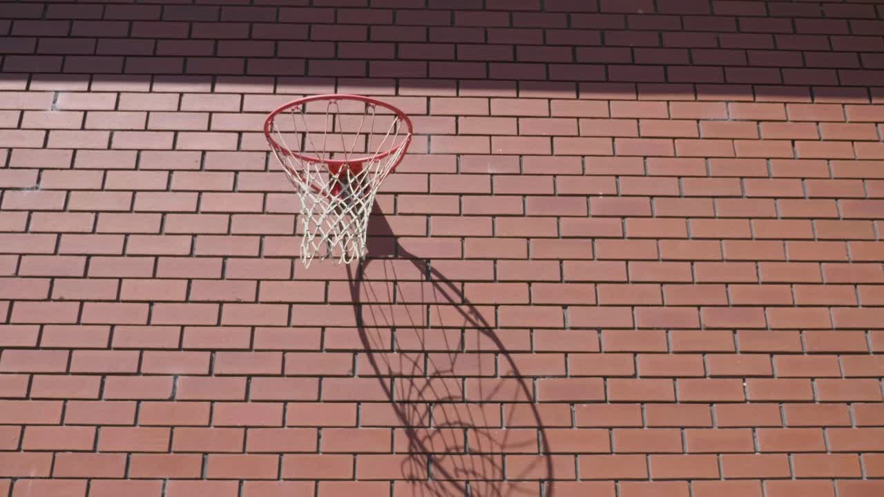 toma frontal más ancha del aro de baloncesto rojo en la pared de ladrillos con la pelota yendo hacia la portería para swish