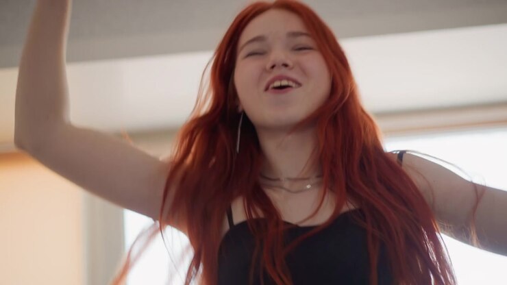 Redheaded woman joyfully singing near window. Lively redhead woman energetically singing with morning light. Cheerful woman with red hair passionately singing during daylight at home window