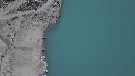 Vista-Aérea-De-Pájaro-De-Los-Barcos-Amarrados-En-La-Orilla-Del-Lago-Attabad