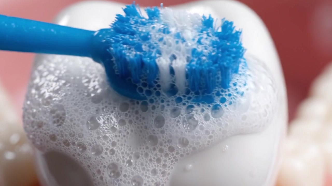 Close-Up of a Tooth Being Brushed with Foamy Toothpaste: Demonstrating Proper Oral Hygiene Techniques and the Importance of Dental Care in Daily Life