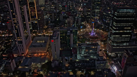 Ciudad-De-México-Aérea-V1-Hiperlapso-Vista-De-Pájaro-Del-ángel-Iluminado-De-La-Independencia-En-El-Paseo-De-La-Reforma,-Inclinación-Hacia-Arriba-Revela-El-Paisaje-Urbano-Del-Centro-Iluminado-Al-Atardecer---Filmado-Con-Mavic-3-Cine---Diciembre-De-2021