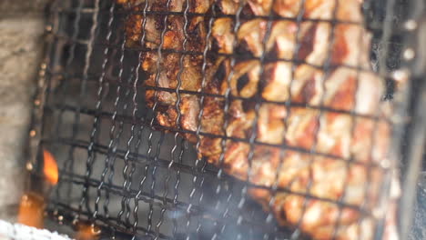 juicy lamb rib in grid dripping fat - barbecue on side of wood fire