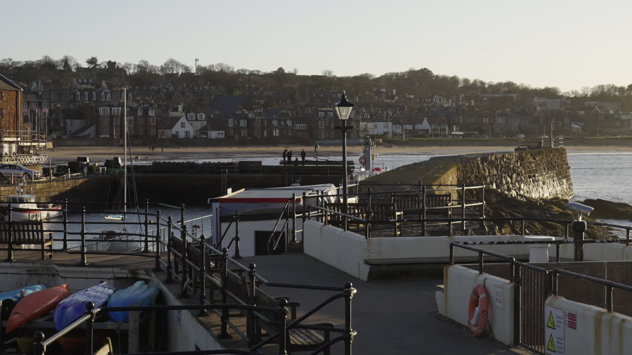 En fredfyldt scene af North Berwick Harbour ved solnedgang med stenvægge, kajakker og kystbyens skyline. Ideel til rejse- og skotsk turismeindhold