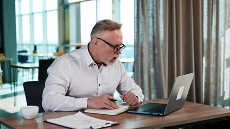 caucasian businessman looks attentively on the screen of his laptop. man working in the office at desk.