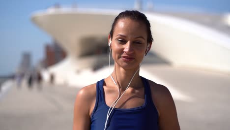 Mujer-Joven-Con-Auriculares-Sonriendo-A-La-Cámara-En-La-Calle