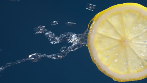 vertical of slow motion macro shot of flowing water from lemon slice on blue-black background