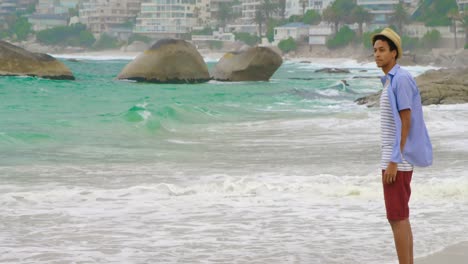 side view of african american man in hat standing on the beach 4k