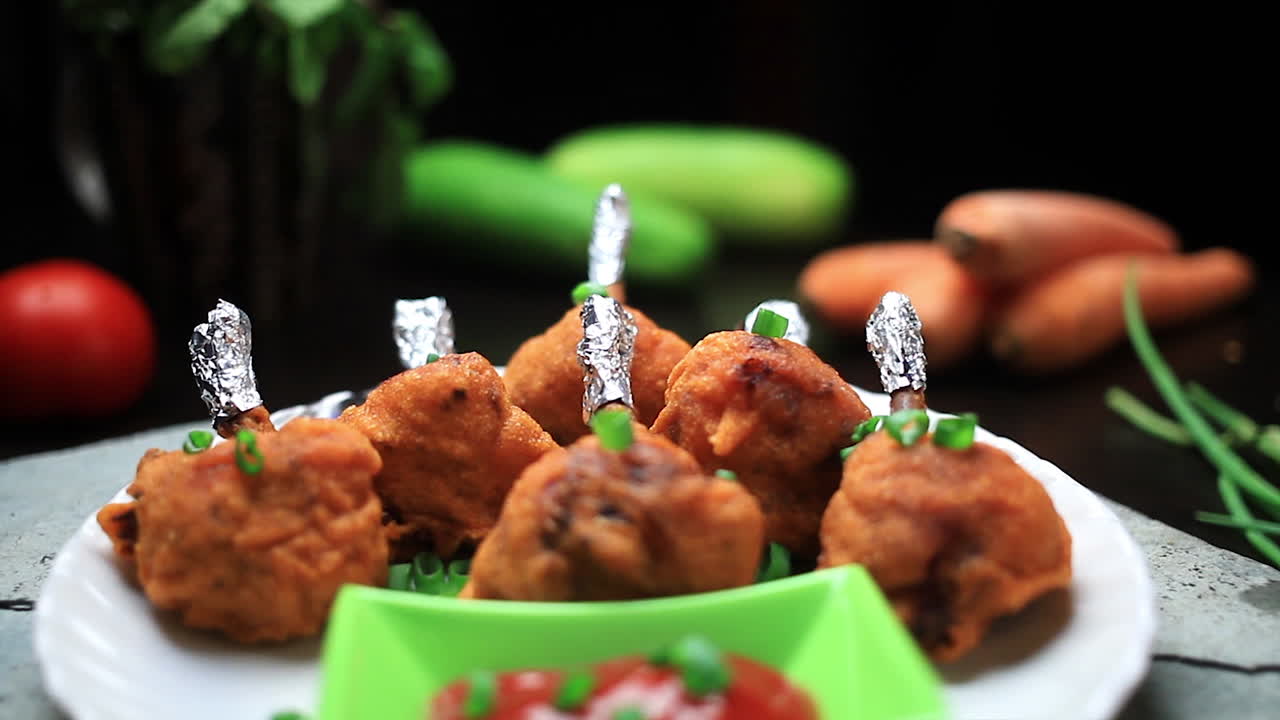 주방장은 요리된 치켄 롤리팝과 토마토 소스를 접시에 담았습니다