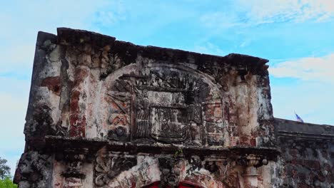 ancient art carvings on the upper wall at the entrance of the heritage a famosa building in melaka malaysia - tilt down pan shot