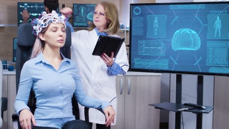 científica femenina en actividad cerebral usando su tableta para hacer ajustes en sus auriculares de paciente