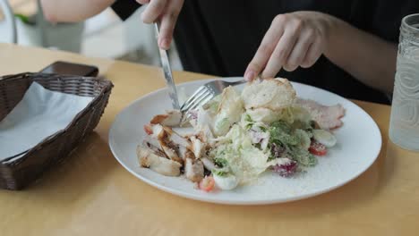 una chica comiendo ensalada en un café.