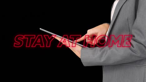 animation of colourful neon words stay at home over caucasian man using a tablet