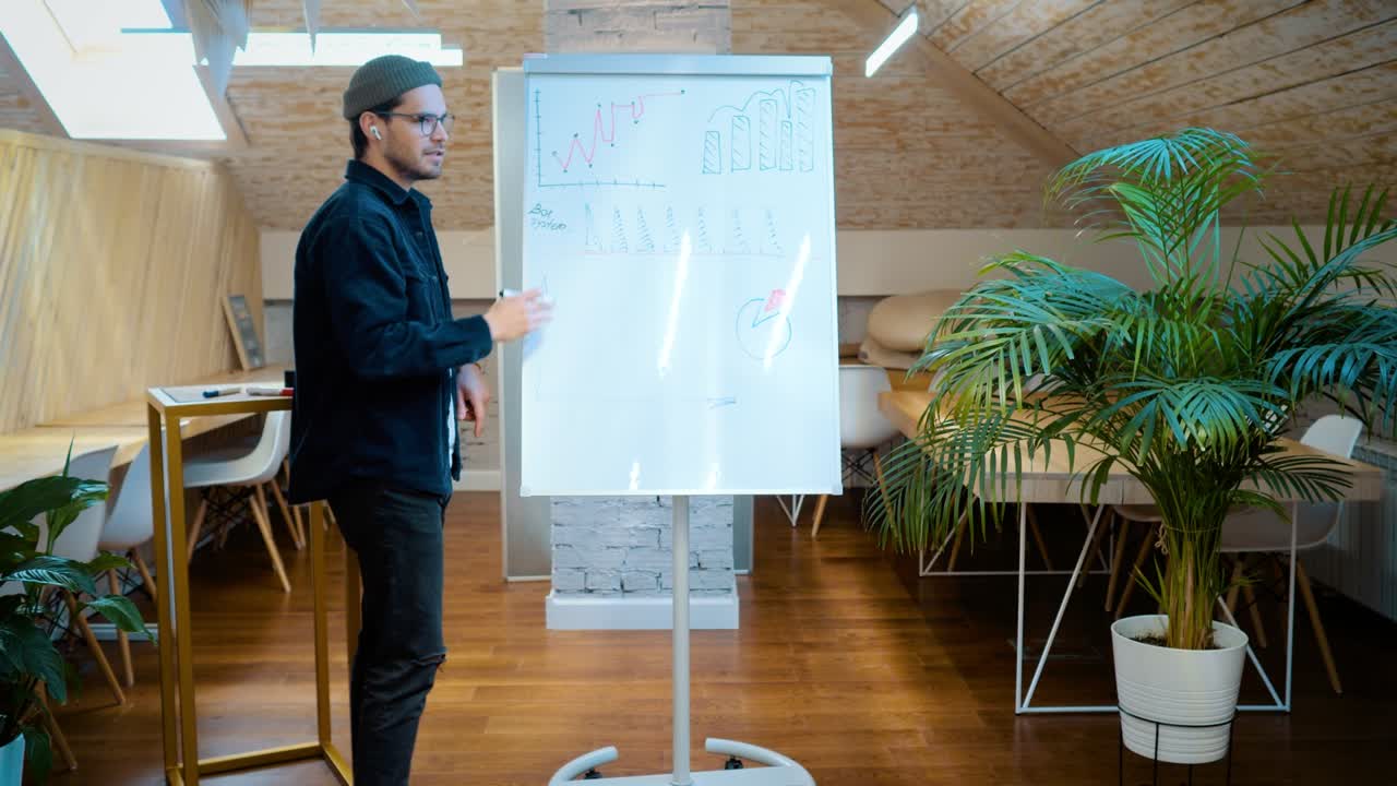 un joven hace una presentación frente a una audiencia. dibuja gráficos en el tablero
