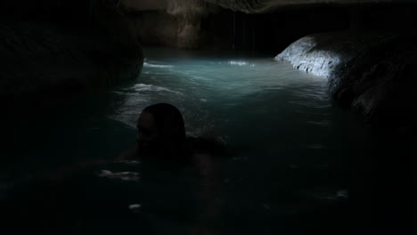 person swimming in a dark cave grotto