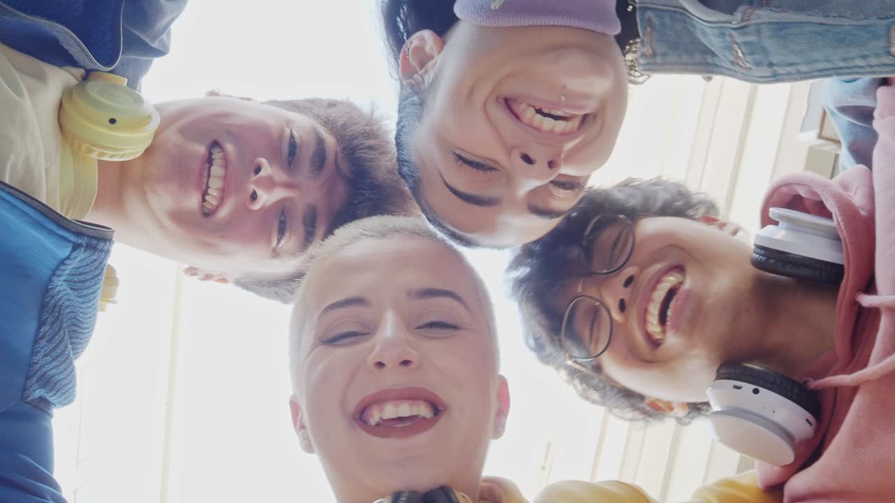 젊은 다민족 학생들의 그룹이 원으로 서서 재미를 느끼고 있습니다.