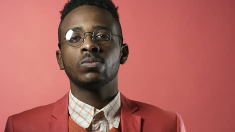 stylish black man posing against pink background