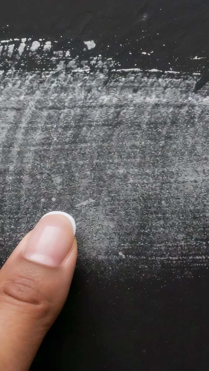 Vertical video: Pressing fingertip dragging on black surface, cleaning chalk line and shifting chip