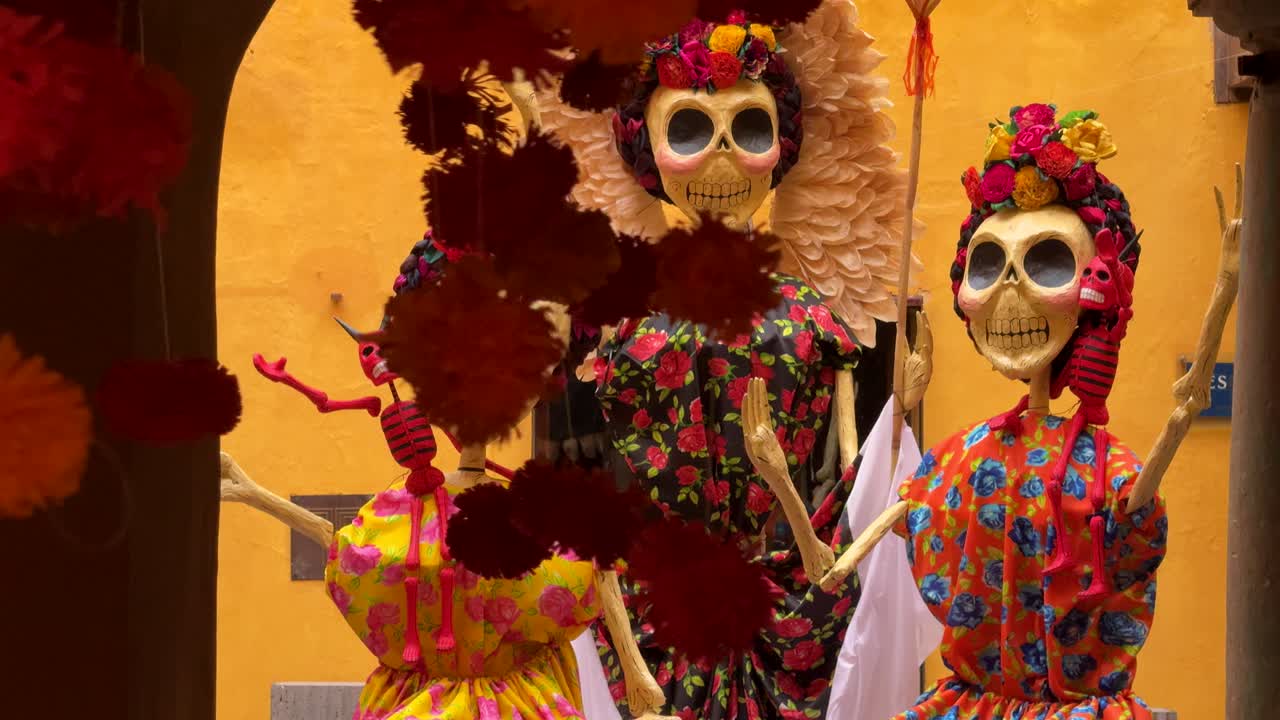Fiori ondeggiano avanti e indietro davanti ai famosi teschi di zucchero Calaveras in questo colorato cortile messicano, in vista delle celebrazioni del Giorno dei Morti