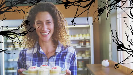 smiling woman holding cupcakes with halloween-themed spider web animation overlay