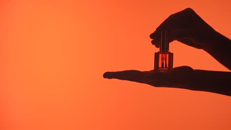 elegant display of nail polish bottle against deep in silhouette a hand gracefully holds a bottle of nail polish silhouetted against a deep orange background emphasizing elegance