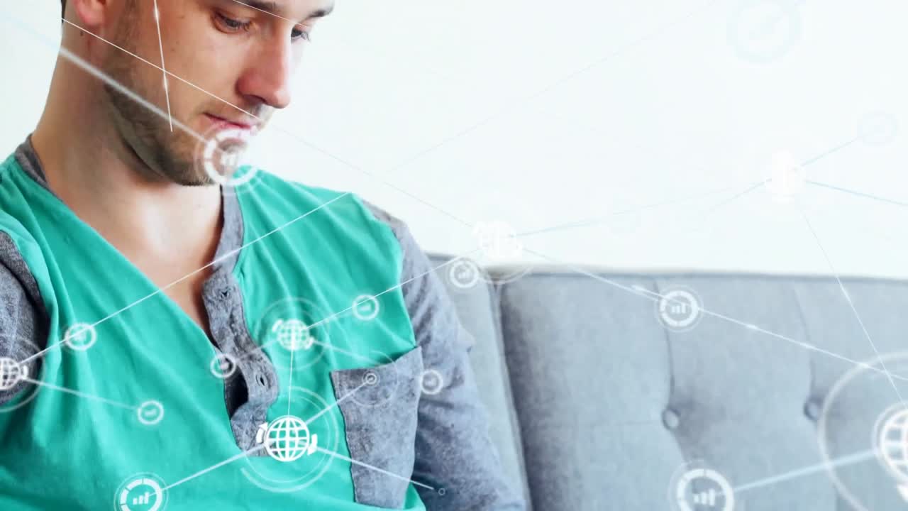 animación de una red de iconos digitales contra un hombre caucásico usando una tableta digital en el sofá en casa