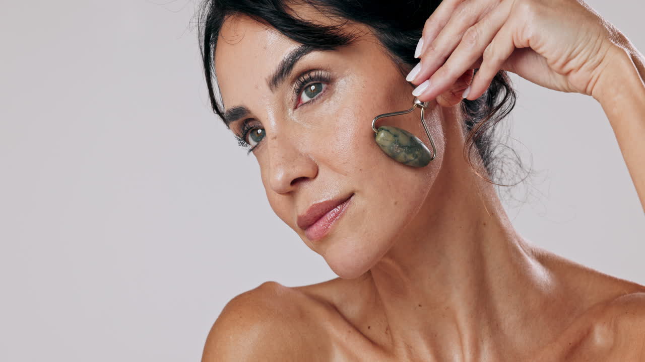 mujer usando un rodillo de jade para el masaje facial