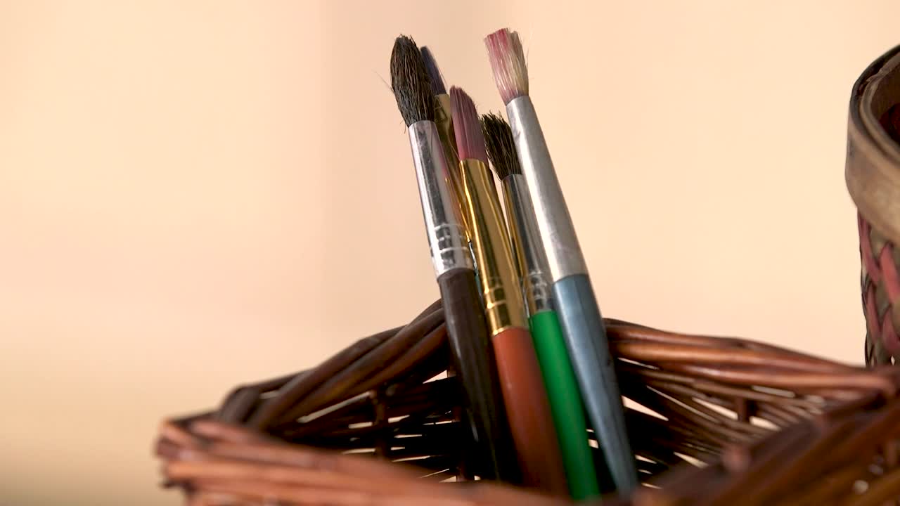 A closeup of paintbrushes in a small wicker holder