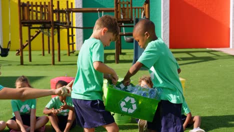 Vista-Lateral-De-Una-Profesora-Caucásica-Enseñando-A-Los-Escolares-Sobre-El-Reciclaje-De-Botellas-En-El-Parque-Infantil-De-La-Escuela.