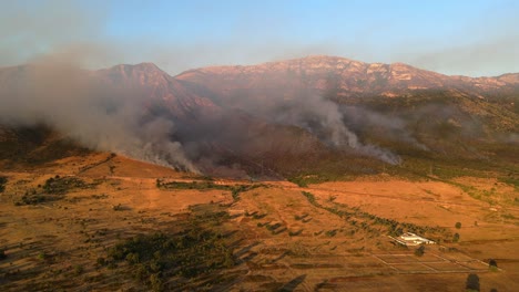 Imágenes-Aéreas-De-Dramáticos-Incendios-Forestales-Ardiendo-En-Las-Montañas-En-Las-Afueras-De-La-Ciudad-De-Vlorë,-Albania,-Iluminadas-Por-Una-Puesta-De-Sol-Naranja.