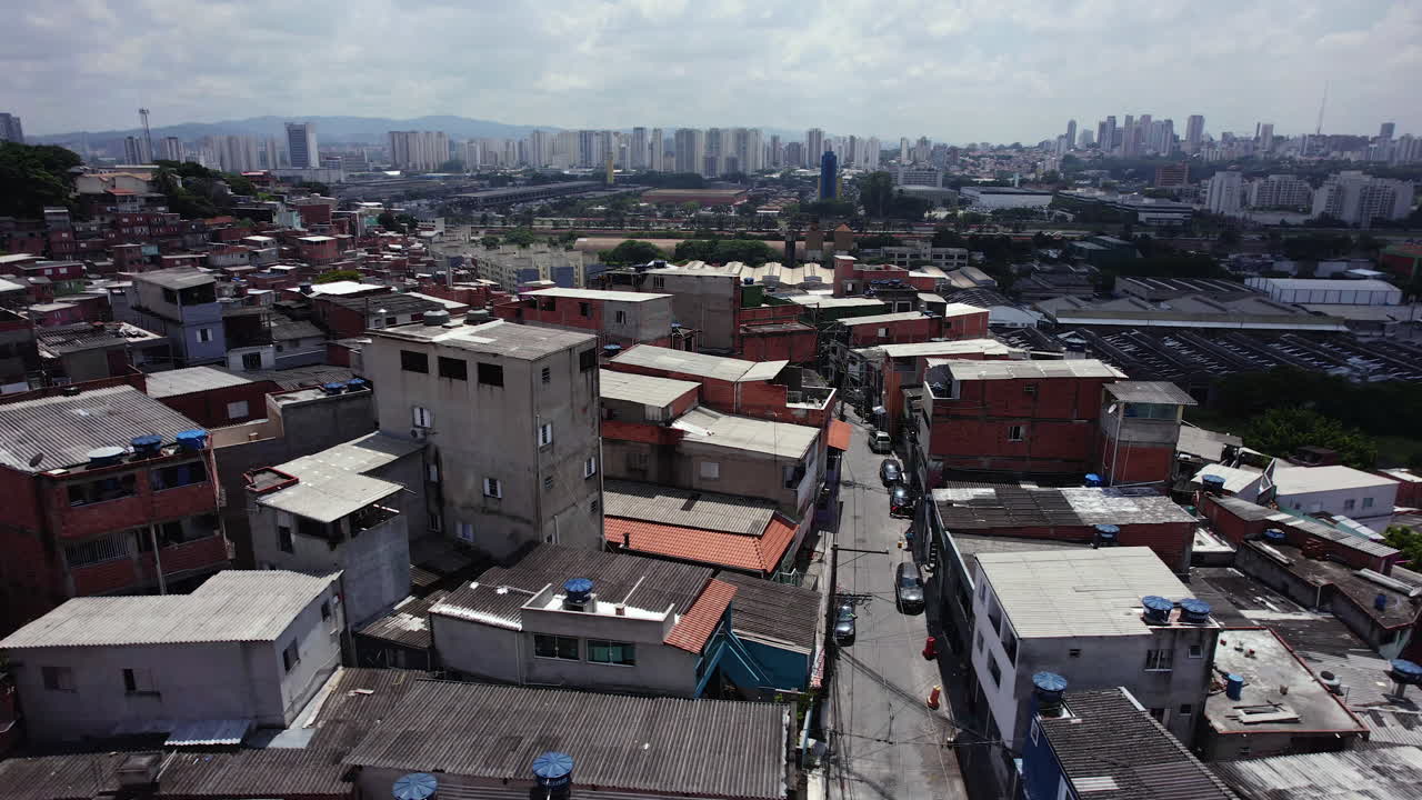 Sobrevoo de drone sobre casas e moradias precárias em Nova Jaguaré, durante o dia em São Paulo, Brasil.