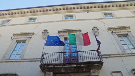 Waving-Flags-On-The-Medieval-Street-Of-Assisi-Town-In-Umbria,-Italy