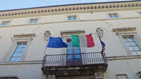 waving flags on the medieval street of assisi town in umbria, italy