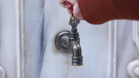 una persona girando una llave para abrir un grifo de agua de época