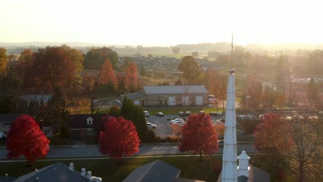 aerial of christian church steeple during dramatic sunset, sunrise in small town in america