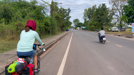 Una-Filmación-Dinámica-De-Una-Mujer-Que-Viaja-En-Bicicleta-Con-Alforjas-Y-Comestibles-En-La-Parte-Trasera