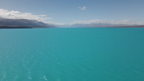 drone flight over stunning blue glacial lake pukaki, new zealand