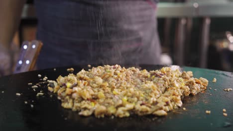 Sprinkling-Fine-Salt-To-Sizzling-Pork-With-Chopped-Onions-And-Green-Chili,-close-up,-slow-motion