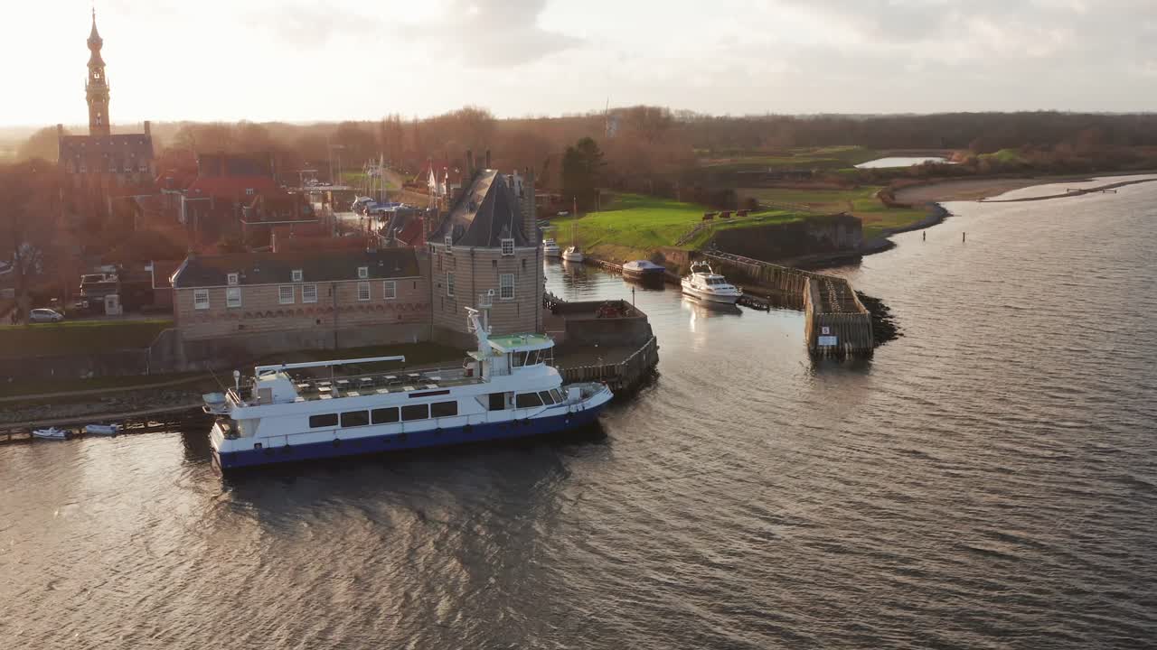 A moored ferry in front of the beautiful touristic city Veere during sunset. Drone shot