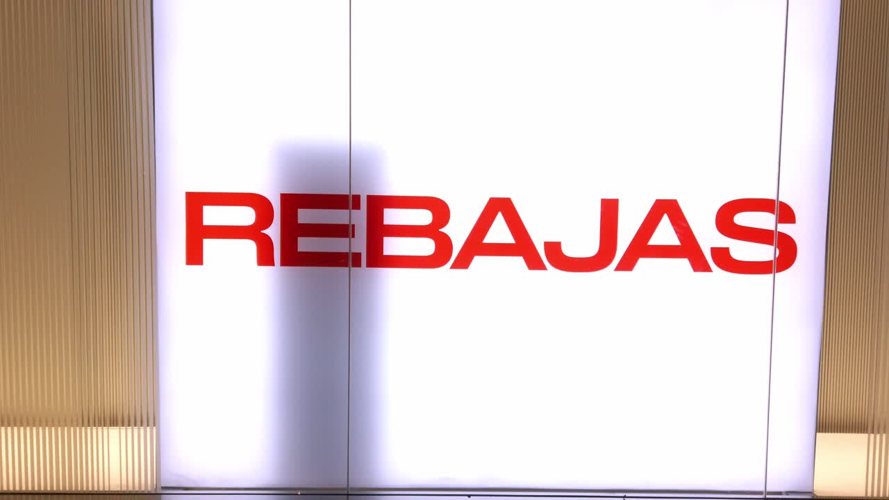Prominent red "REBAJAS" sign zooming out in modern store with bright white background