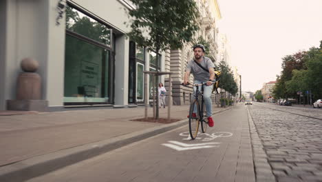 food delivery courier wearing thermal backpack rides a bike through the streets of the city to deliver orders for clients and customers