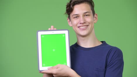 young handsome teenage boy showing digital tablet