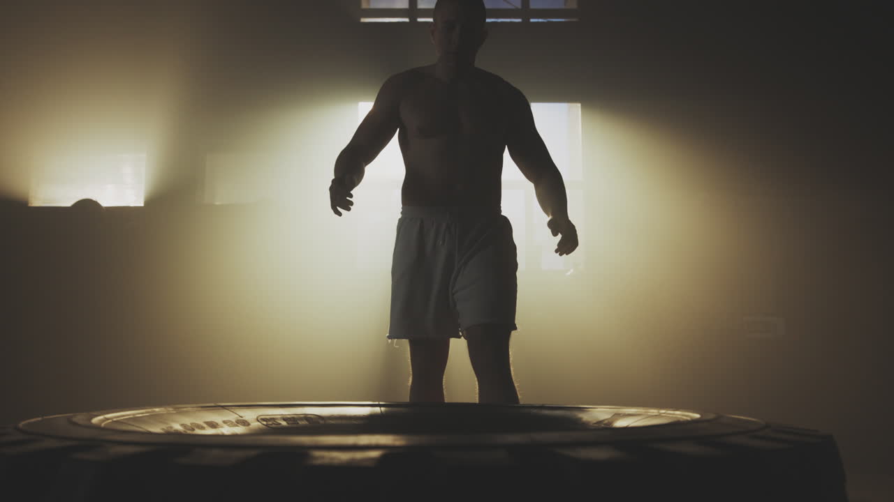 Man Performing Tire Flips in a Gym