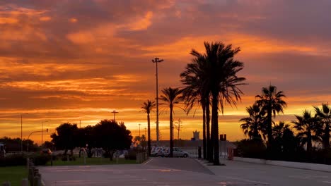 Cinematic-4K-cityscape-in-motion-of-Cascais-at-a-stunning-early-morning-sunrise-facing-the-city-with-palm-trees-and-cars-in-the-empty-parking-lot